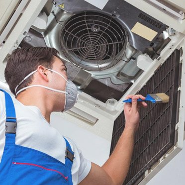 an ac technician cleaning air ducts on an ac maintenance service