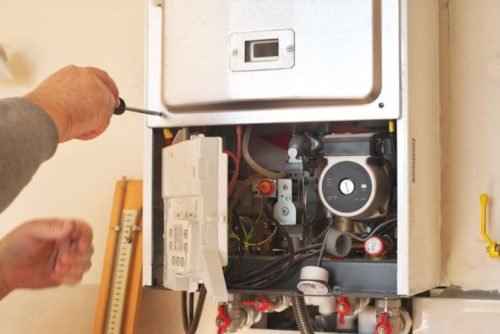 an HVAC technician next to a heater unit on a heating service